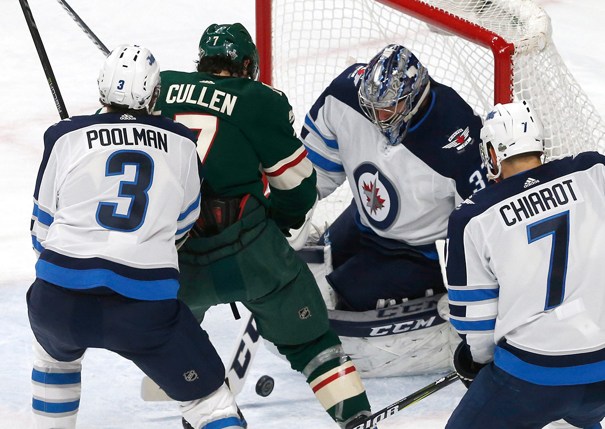 Winnipeg Jets goalie Connor Hellebuyck stops a scoring attempt by Minnesota Wild's Matt Cullen, second from left, during the second period of Game 4 of an NHL hockey first-round playoff series Tuesday, April 17, 2018, in St. Paul, Minn. 