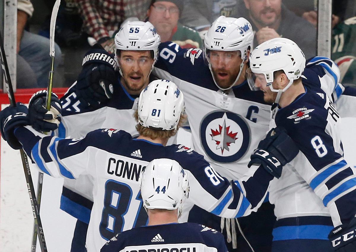 Winnipeg Jets celebrate with Mark Scheifele, top left, after he scored on Minnesota Wild goalie Devan Dubnyk during the first period of Game 4 of an NHL hockey first-round playoff series Tuesday, April 17, 2018, in St. Paul, Minn. 