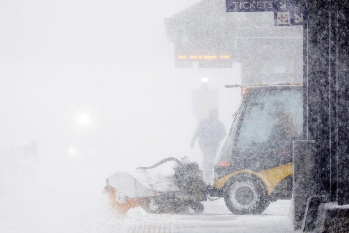 A worker tries to clear snow and ice from the Metro Government Center Plaza station as the snow picked up in downtown Minneapolis Saturday, April 14, 2018.   The National Weather Service predicts 9 to 15 inches of snow across a large swath of southern Minnesota including the Twin Cities before it's all over. (Anthony Souffle/Star Tribune via AP).