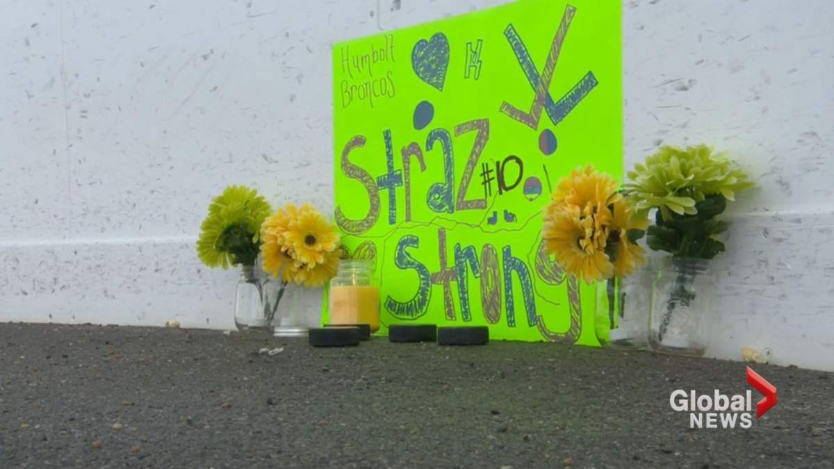 A poster, candle and flowers are seen at a vigil held in Airdrie in support of Humboldt Broncos player Ryan Straschnitzki and the other victims of last week’s deadly crash.
