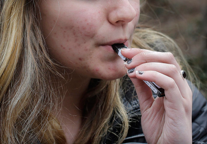 In this Wednesday, April 11, 2018 photo, an unidentified 15-year-old high school student uses a vaping device near the school's campus in Cambridge, Mass. 