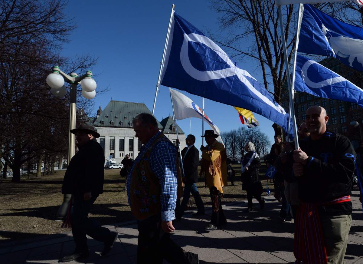 File - David Chartrand, president of the Manitoba Metis Federation, middle, carries the Metis flag as he and fellow Metis Federation leaders and delagates march to the Supreme Court of Canada in Ottawa on Thursday, April 14, 2016. 