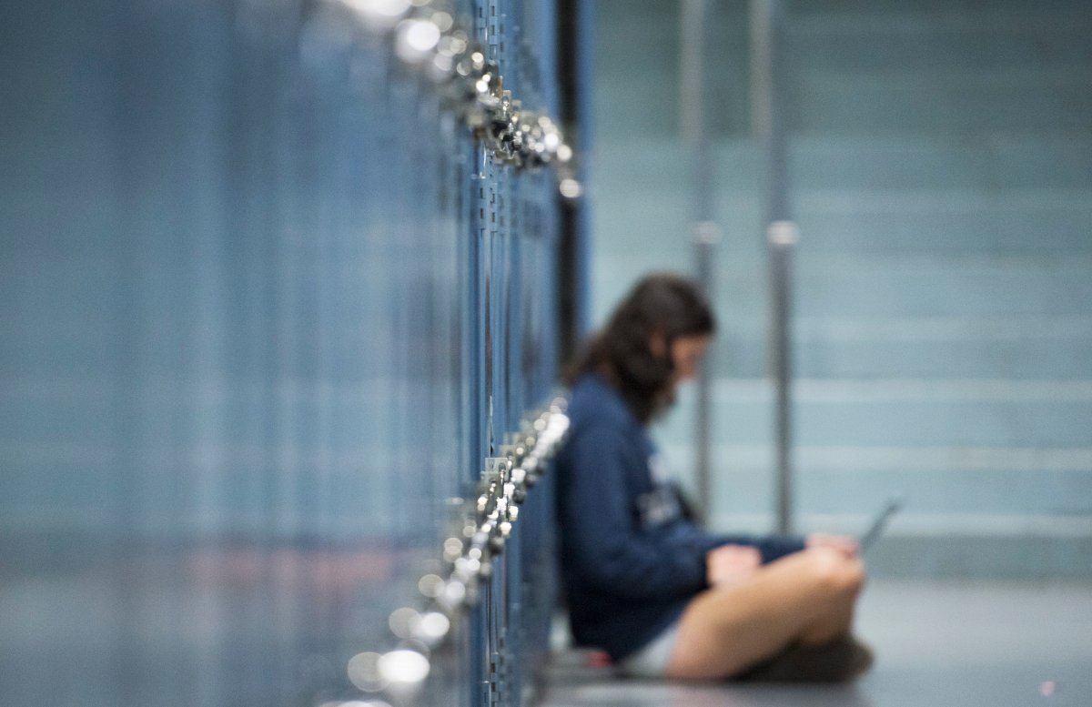 A female student works on her laptop next to lockers at Dawson College in Montreal.