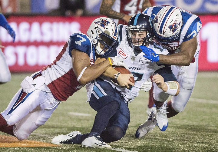 Toronto Argonauts quarterback Cody Fajardo, centre, is tackled by Montreal Alouettes' John Bowman (7) and Kyries Hebert during second half CFL football action in Montreal, Friday, August 11, 2017. The Alouettes announced Kahlil Carter has stepped down as defensive co-ordinator of the Montreal Alouettes for personal reasons but will remain with the club as a scout. Thursday, May 10, 2018.