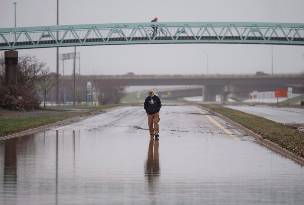 A pedestrian walks along a closed street in downtown Fredericton, N.B., as floodwaters from the St. John River remain level on Monday, April 30, 2018.