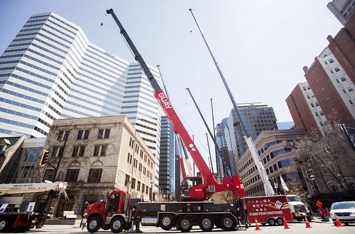 Crane operators raise the arms of their cranes during a protest in Montreal, Saturday, May 5, 2018. 