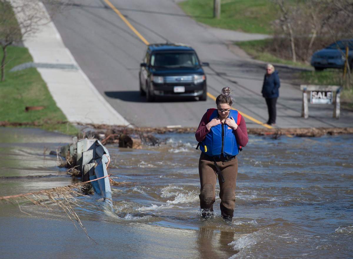 A Saint John, N.B. woman watches her step as she wades across a flooded road to get to work on Saturday, May 5, 2018.
