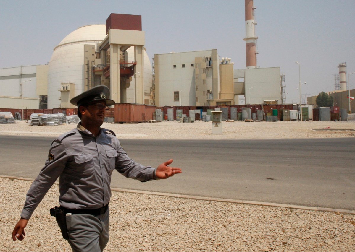 In this Aug. 21, 2010 file photo, an Iranian security official directs media at the Bushehr nuclear power plant, with the reactor building seen in the background, just outside the southern city of Bushehr, Iran.