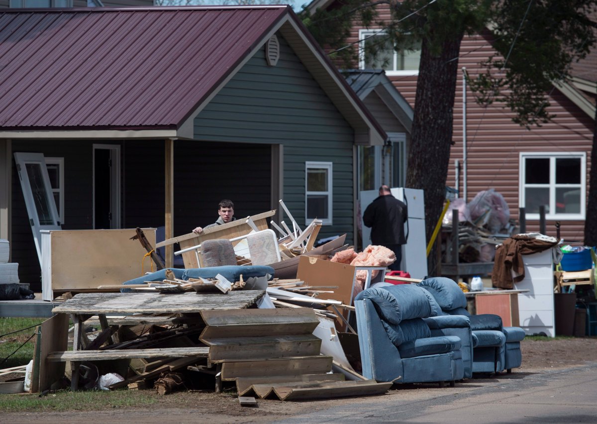 Families load debris from their homes and cottages on the road as floodwaters from the Saint John River recede in Princess Park, N.B. on Saturday, May 12, 2018. 
