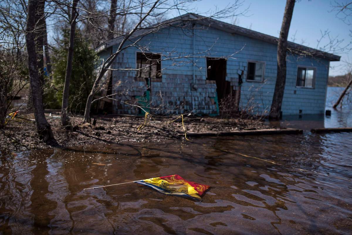 A New Brunswick flag floats in front of a cottage destroyed by flooding from the Saint John River in Waterborough, N.B., on Sunday, May 13, 2018. 