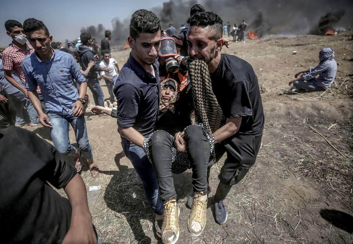 Palestinian protesters carry a wounded female protester during clashes after protests near the border with Israel in the east of Gaza Strip.
