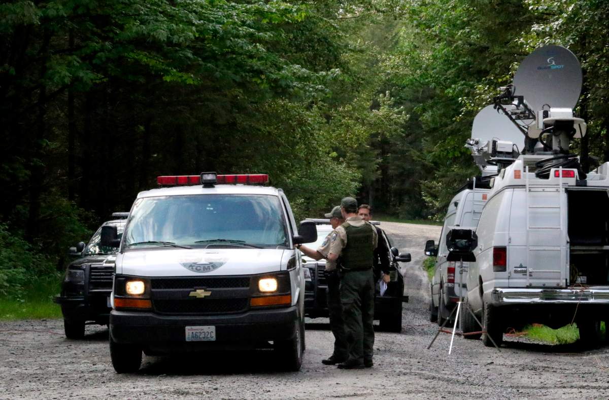 Washington State Fish and Wildlife Police confer with an individual from the King County Medical Examiner’s office on a remote gravel road above Snoqualmie, Wash., following a fatal cougar attack.