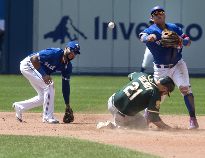 Toronto Blue Jays' Richard Urena and teammate Yangervis Solarte manage to force out Oakland Athletics' Jonathan Lucroy at second base during sixth inning American League MLB baseball action in Toronto on Sunday May 20, 2018. 