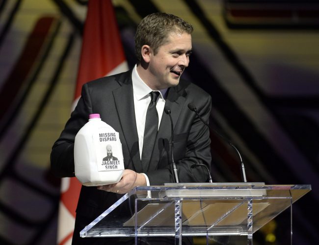 Conservative Leader Andrew Scheer holds up a jug of milk as he jokes during his speech at the Parliamentary Press Gallery Dinner at the Museum of History in Gatineau, Quebec on Saturday, May 26, 2018.