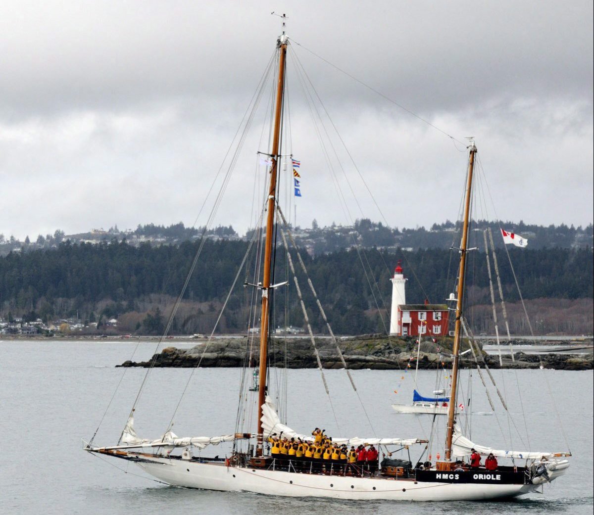 HMCS Oriole passes Fisgard Lighthouse in Victoria as the crew wave farewell as they start their journey to Halifax in a March 16, 2017 handout photo. 
