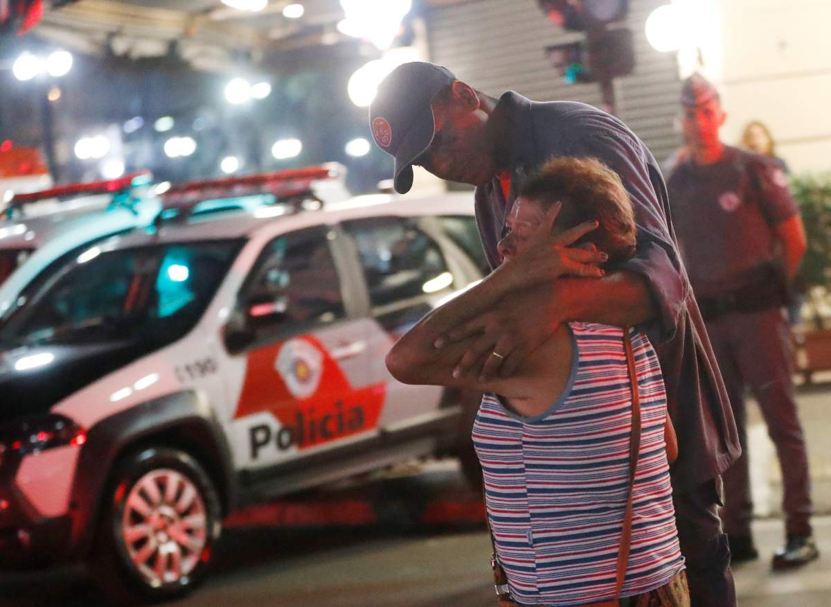 Police officer comforts a woman near the site where a building collapsed in downtown Sao Paulo, Brazil.