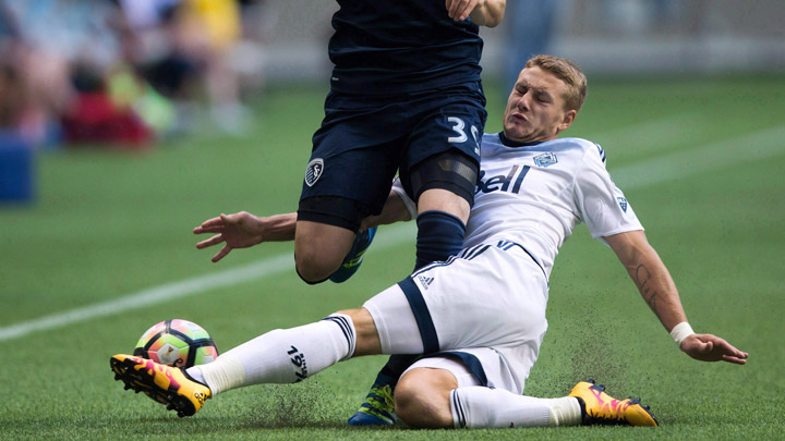 Vancouver Whitecaps' Brett Levis, right, slides to take the ball away from Sporting Kansas City's Cameron Porter during first half CONCACAF Champions League soccer action in Vancouver, B.C., on Tuesday August 23, 2016. 