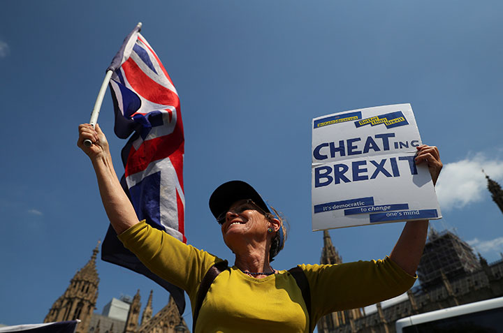 An anti-Brexit protester waves EU and Union flags and holds up a placard opposite the Houses of Parliament, on a sunny day in London, May 8, 2018. 