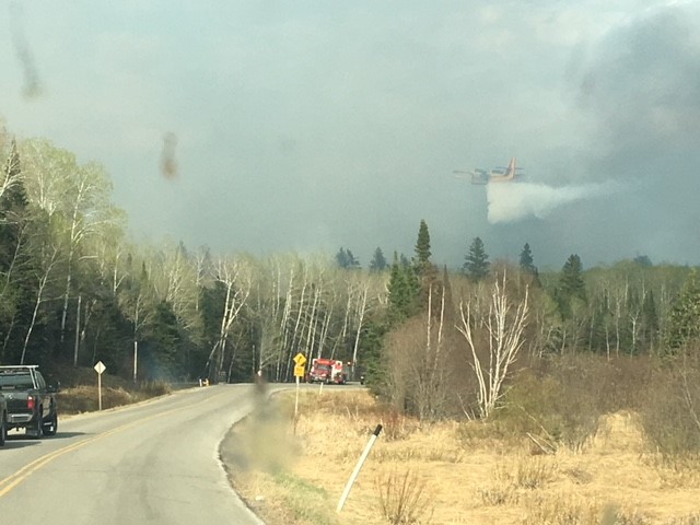 A water bomber targets flames raging near Caddy Lake Sunday. Cottagers were told to leave the area.