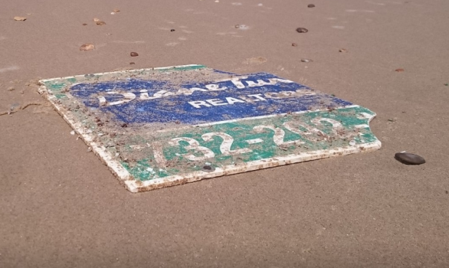 Realty sign lost during Superstorm Sandy ends up on French beach - image