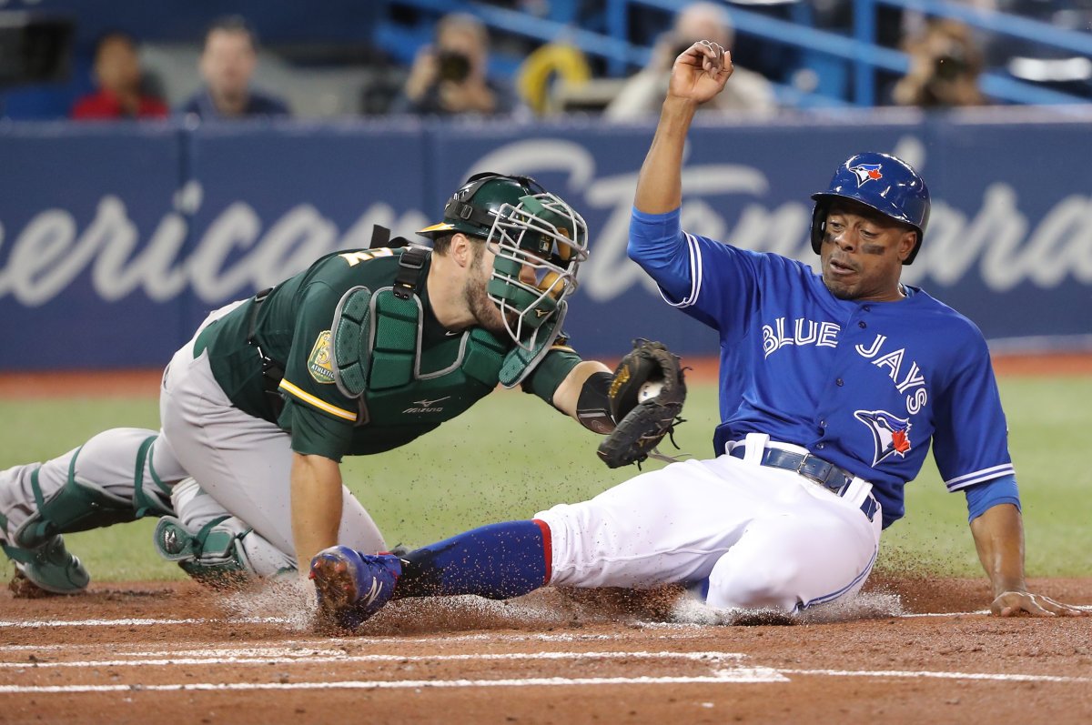 TORONTO, ON - MAY 18: Curtis Granderson #18 of the Toronto Blue Jays is tagged out at home plate trying to score by Josh Phegley #19 of the Oakland Athletics in the first inning during MLB game action at Rogers Centre on May 18, 2018.