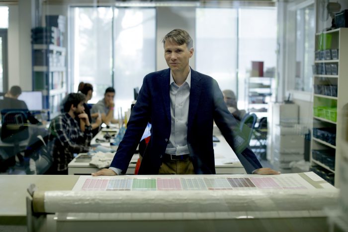 Seen through an internal window, the founder and CEO of "My Nametags" Lars Andersen, originally from Norway, poses for photographs by a sheet label "weeding machine" at his business premises in London, Wednesday, May 23, 2018.