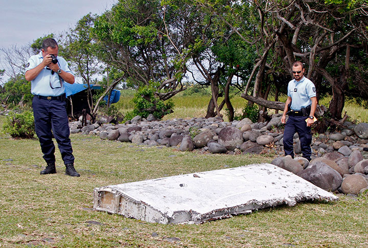 FILE - In this July 29, 2015 file photo, French police officers look over a piece of debris from a plane in Saint-Andre, Reunion Island.