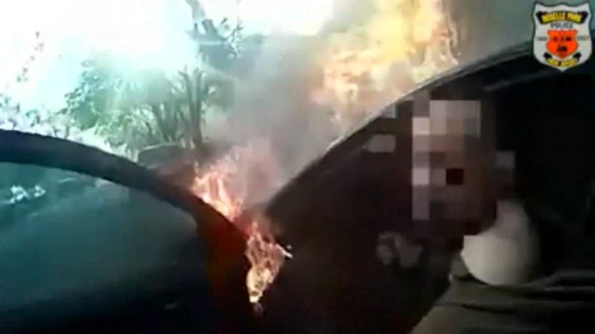 Flames are seen engulfing the engine compartment of a vehicle in Roselle Park