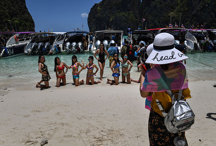 This photo taken on April 9, 2018 shows tourists posing in swimsuits in front of a row of speedboats in Maya Bay, on the southern Thai island of Koh Phi Phi.