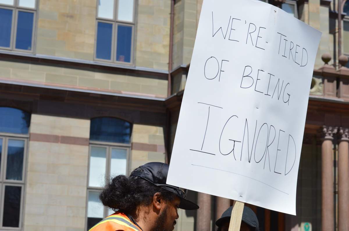 A man holds a sign at a protest against a lack of diversity and discriminatory hiring practices at the Halifax Regional Municipality .