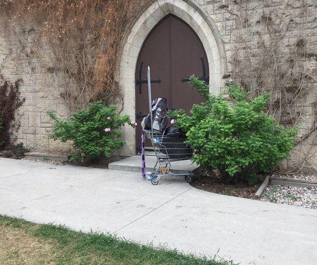 A shopping cart filled with belongings sits outside All Saints’ Anglican Church where a tent city is being dismantled.