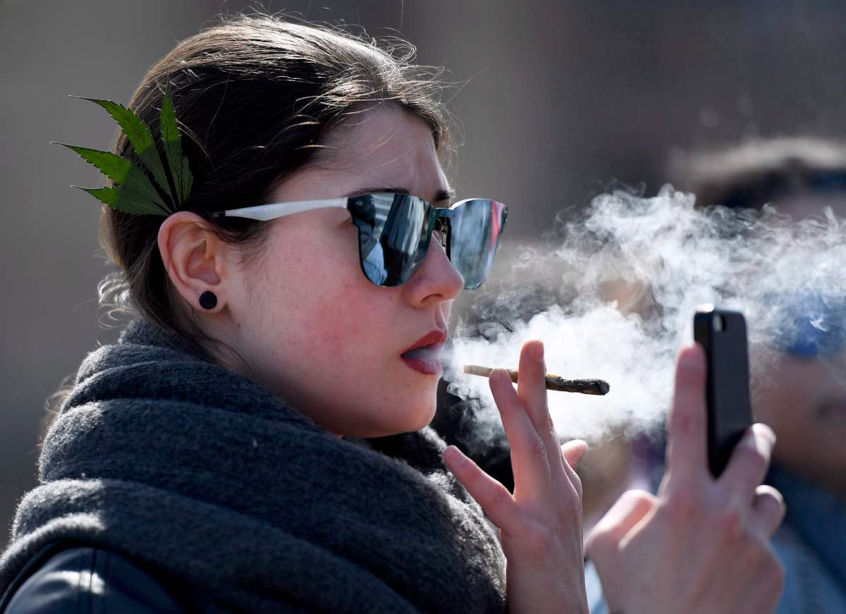 A woman smokes a joint during the annual 4/20 marijuana celebration on Parliament Hill in Ottawa on Friday, April 20, 2018.
