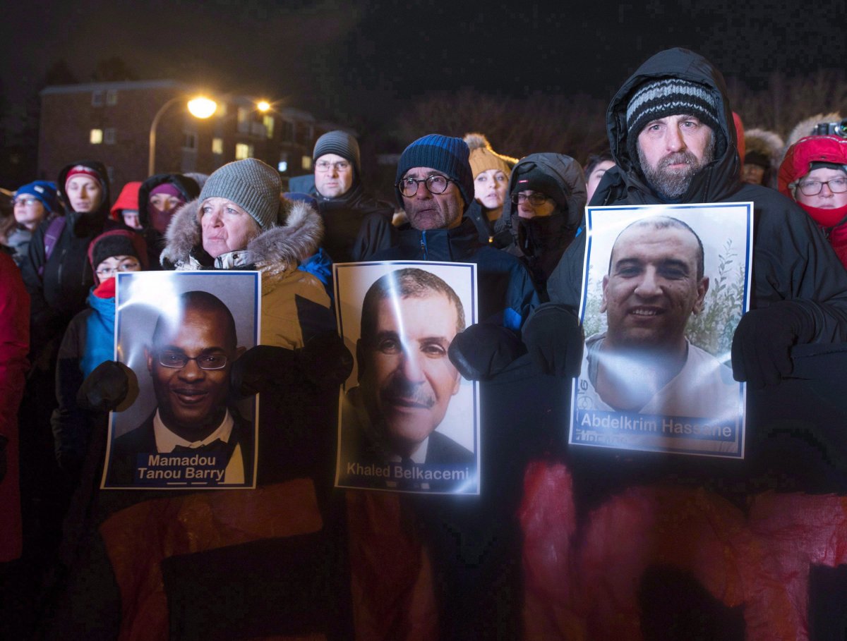 People hold pictures of the victims at a vigil to commemorate the one-year anniversary of the Quebec City mosque shooting, in Quebec City, Monday, Jan. 29, 2018. 