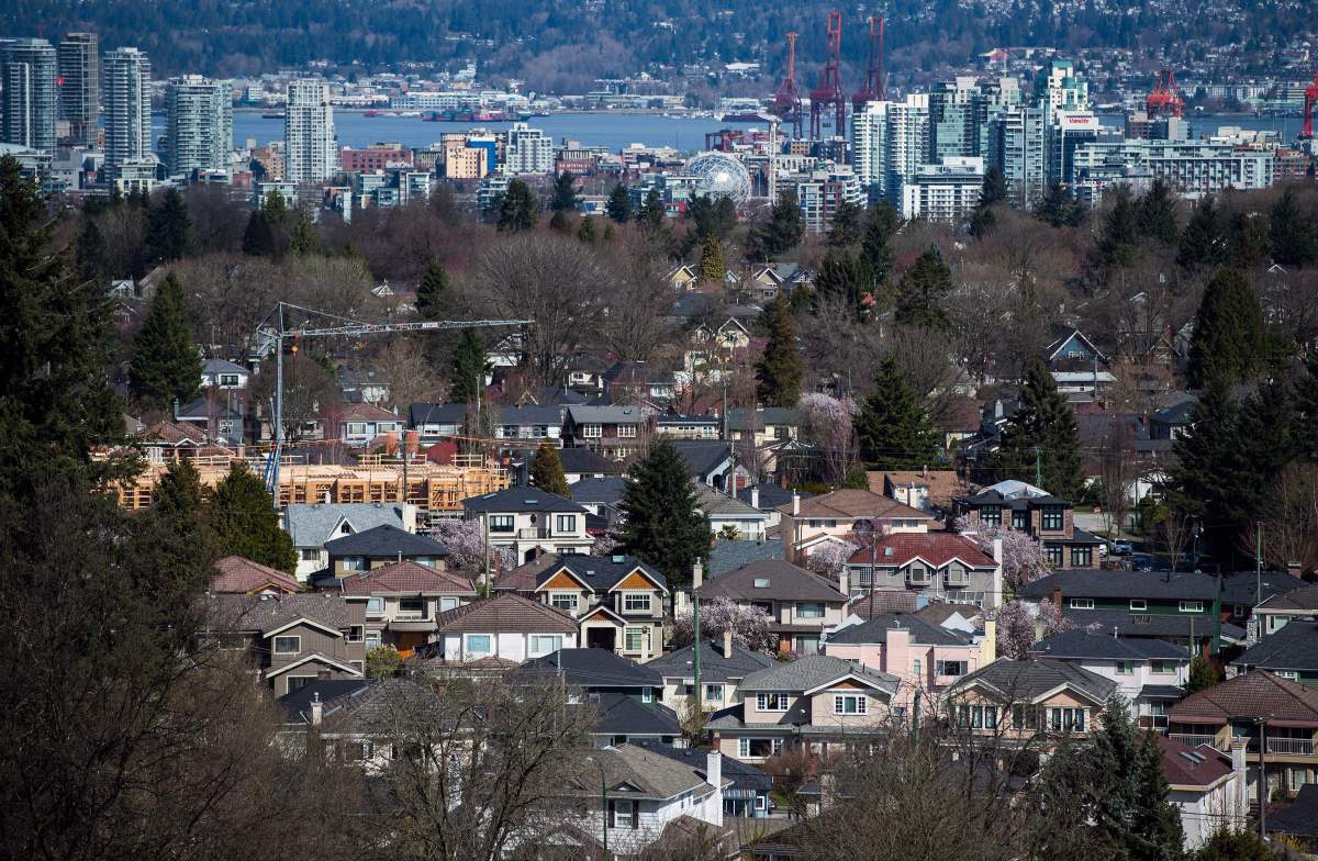 A condo building is seen under construction surrounded by houses as condo towers are seen in the distance in Vancouver, B.C., on Friday March 30, 2018.