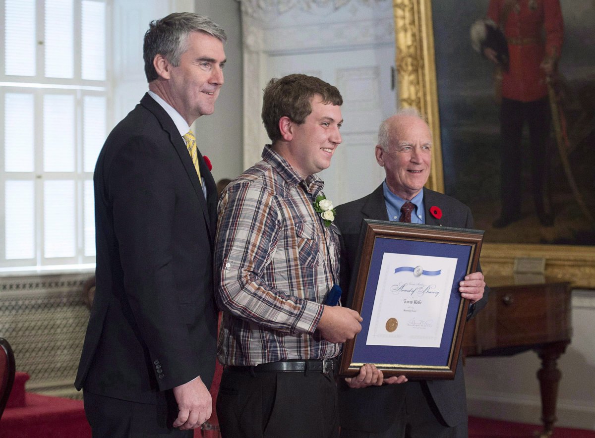 Premier Stephen McNeil, left, and advisory board chair Hugh Laurence, flank Travis Wolfe, a Nova Scotia Medal of Bravery recipient, at Province House in Halifax on Wednesday, Nov. 8, 2017. 