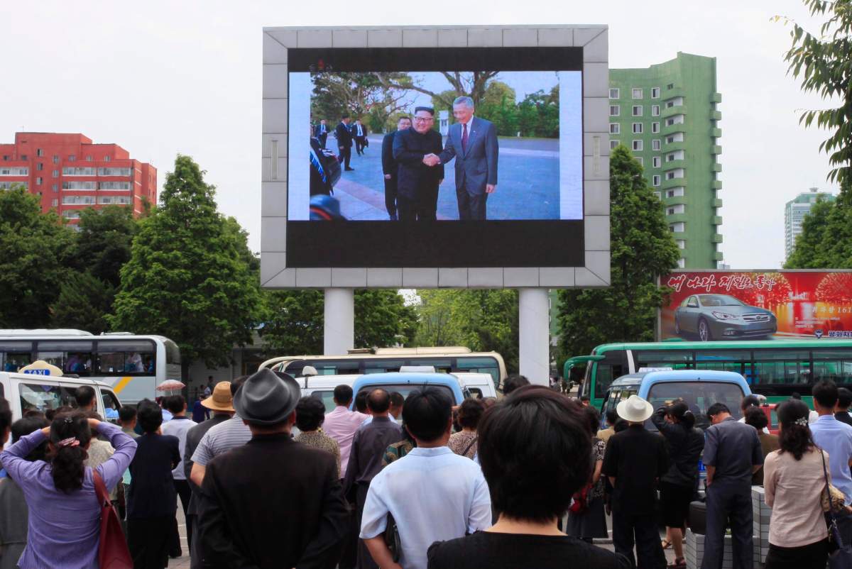 People watch a large screen at the main train station airing video of North Korean leader Kim Jong Un being greeted by Singapore Prime Minister Lee Hsien Loong in Pyongyang, North Korea, Monday, June 11, 2018.