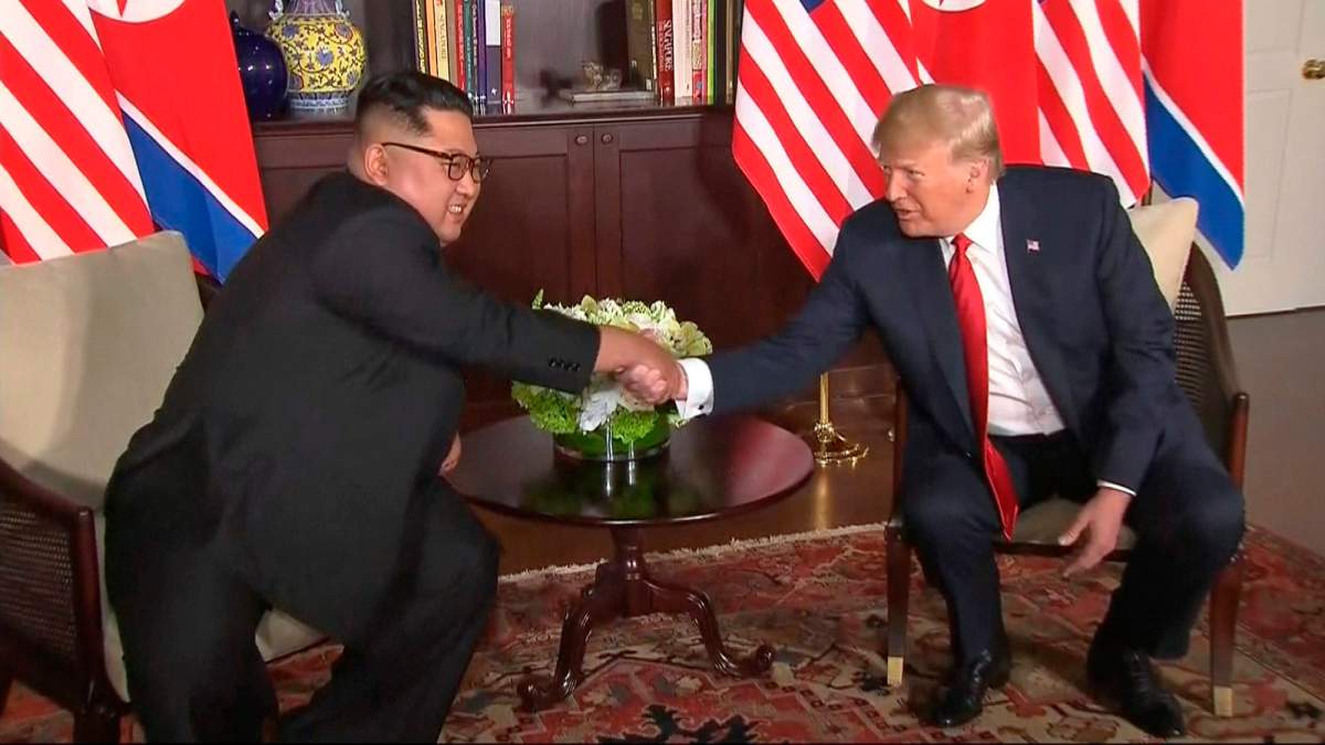 In this image made from video provided by Host Broadcaster Mediacorp Pte Ltd,, U.S. President Donald Trump and North Korean leader Kim Jong Un shake hands ahead of their meeting at Capella Hotel in Singapore, Tuesday, June 12, 2018. (Host Broadcaster Mediacorp Pte Ltd via AP).