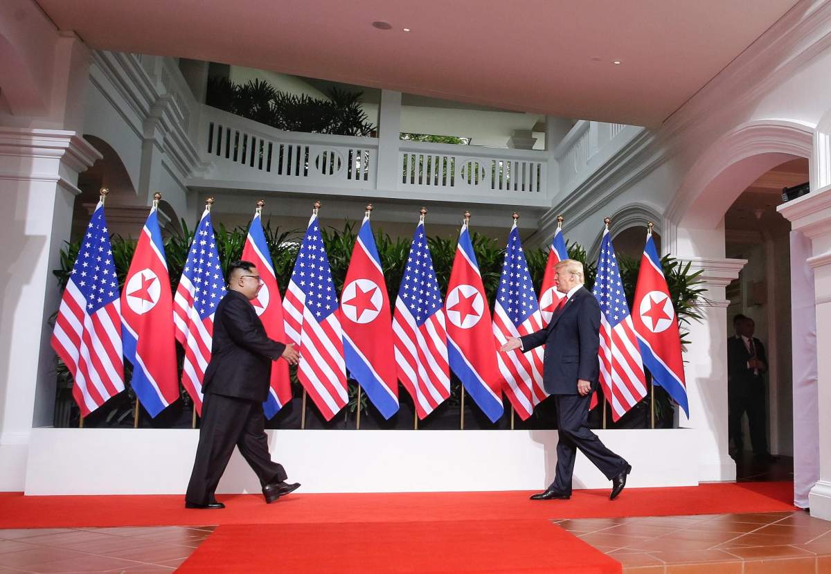 U.S. President Donald J. Trump (R) and North Korean leader Kim Jong-un (L) walk towards each other to shake hands at the start of a historic summit at the Capella Hotel on Sentosa Island, Singapore, June 12, 2018.