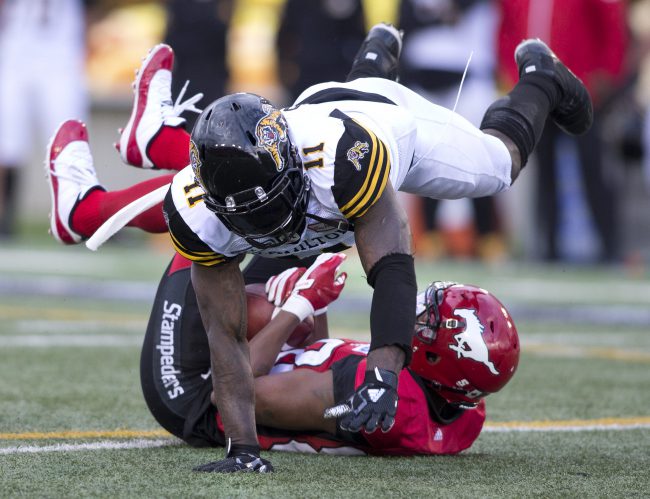 Hamilton Tiger-Cats player Larry Dean, top, tackles Calgary Stampeders player Kamar Jorden during second half CFL action in Calgary, Ab. on Sat., June 16, 2018.  