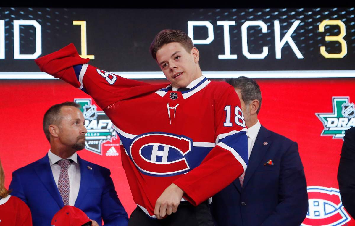 Jesperi Kotkaniemi, of Finland, dons a Carolina Hurricanes jersey after being chose by the team during the NHL hockey draft in Dallas, Friday, June 22, 2018. 