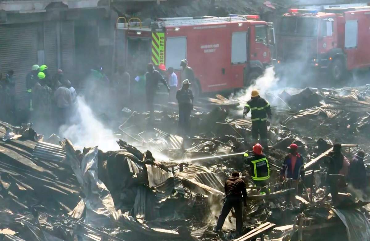 In this image from TV, a fire fighter damps down the charred debris after a fire swept through a marketplace in Nairobi, Kenya, Thursday June 28, 2018.