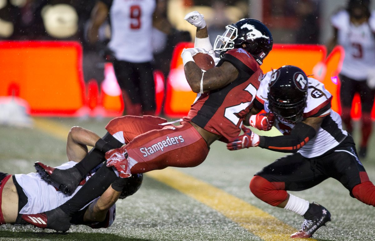 Calgary Stampeders player Don Jackson, ctr, scores a touchdown pushing past Ottawa Redblacks players Antoine Pruneau, lt, and Josh Johnson during late 4th quarter CFL action against the  in Calgary, Ab. on Thursday, June 28, 2018.  (CFL PHOTO - Larry MacDougal).