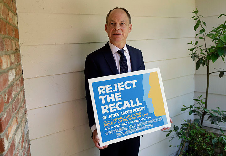 In this May 15, 2018 file photo, Judge Aaron Persky poses for a photo with a sign opposing his recall in Los Altos Hills, Calif. 