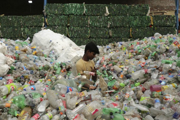 An Indian worker sorts used plastic bottles before sending them to be recycled at an industrial area on the outskirts of Jammu, India, Tuesday, June 5, 2018.