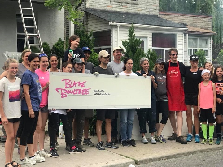 A group of volunteers hold up the BBYOS sign as they begin renovations on Saturday.