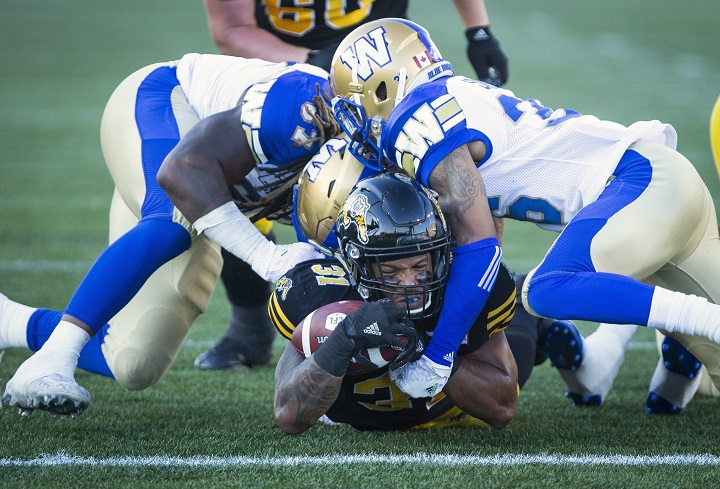Hamilton Tiger-Cats running back Sean Thomas Erlington (31) gets to the one yard line while being tackled by Winnipeg Blue Bombers defensive tackle Cory Johnson (67), left, and Winnipeg Bluebombers defensive back Marcus Sayles (36) during first quarter CFL game action in Hamilton, Ontario on Friday, June 29, 2018. 