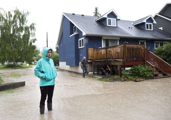 A woman walks stands in the backyard of her home in the flooded community of Bowness as up to 100,000 people have been evacuated from their homes, in Calgary, on June 21, 2013. The federal public safety minister says the government will open its wallet to help Canadians prepare for natural catastrophes spawned by extreme weather linked to climate change. THE CANADIAN PRESS/Nathan Denette