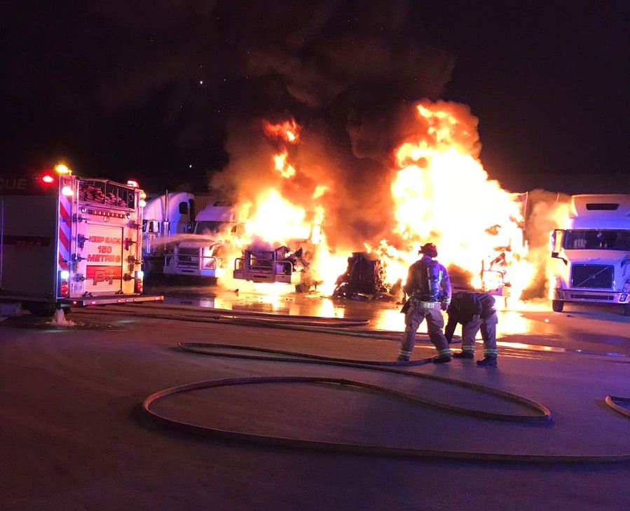 Transport trucks seen engulfed in flames at Trans 99 in early Wednesday morning fire.