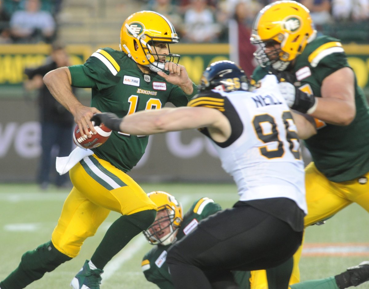 Edmonton Eskimos player #13 (QB) Mike Reilly tries to get away from Hamilton Tiger-Cats player #96 (DL) Jason Neill during the 2nd quarter of CFL game action between the Edmonton Eskimo's and the Hamilton Tiger-Cats at the Brick Field located at Commonwealth stadium in Edmonton Friday, June 22 /2018. 