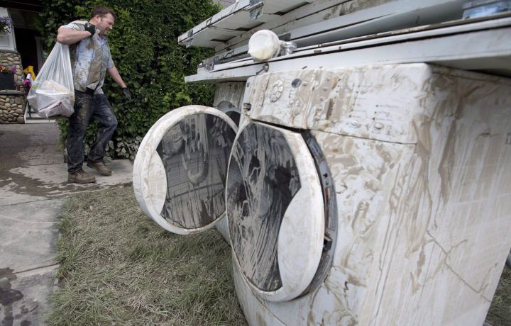 A man helps a friend move furniture and personal belongings out of his mud-soaked basement near downtown Calgary, June 23, 2013.
